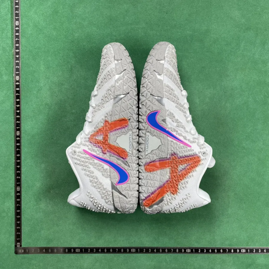 Green-background QC photo of sneaker soles with ruler